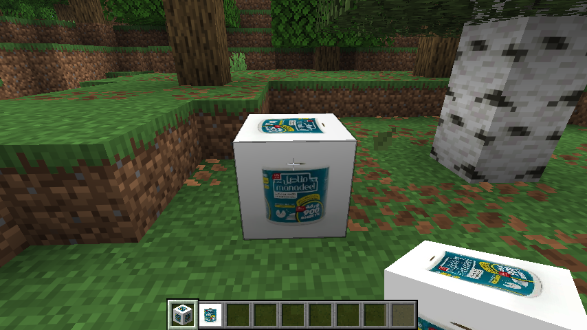 A white Manadeel tissue-box block placed on grass in a Minecraft forest, with a second box held in the hotbar.